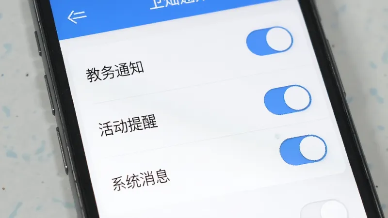 卫灿App消息通知设置界面，手机屏幕显示通知分类开关列表，包括教务通知、活动提醒、系统消息等选项，界面配色为白底蓝字，开关按钮清晰醒目，风格简约现代，画质干净无杂乱元素