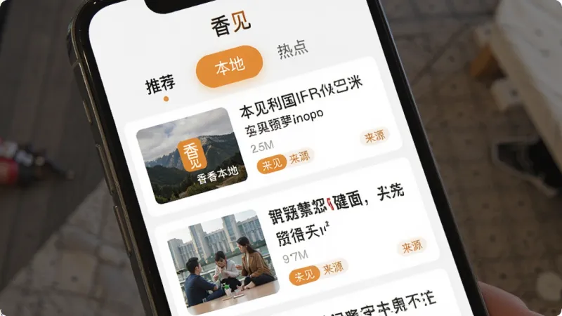 香见App本地资讯频道界面,手机屏幕显示新闻列表卡片,每条卡片包含缩略图、标题和来源标签,顶部有“推荐”“本地”“热点”等频道分类标签,界面以白色为底,点缀暖橙色高亮,风格清爽,画质清晰,屏幕中显示“香见”文字