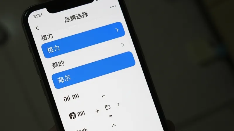 一张展示红外遥控（遥控空调）软件海量码库的界面截图，画面中手机屏幕显示着品牌选择列表，列表中有格力、美的、海尔、小米等品牌名称，界面设计为白色背景搭配蓝色高亮选中项，布局清晰，风格简洁，画质干净，无多余元素。
