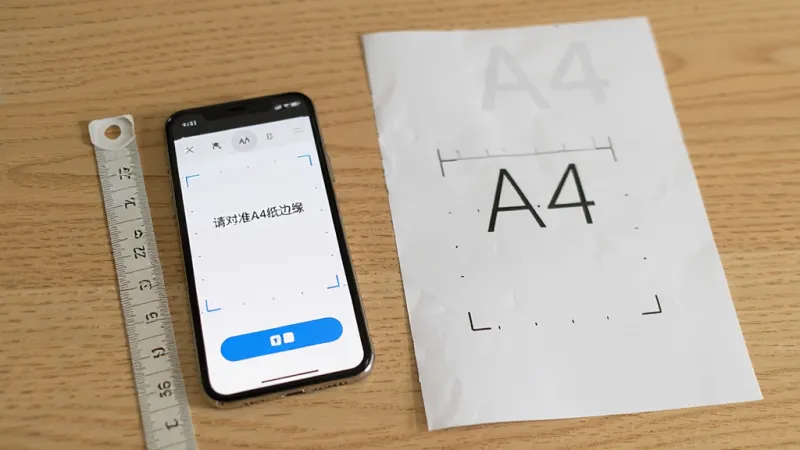 免费尺子测距王 手机放在桌面上 旁边有一张A4纸 屏幕显示校准界面 文字提示