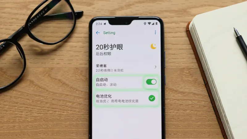 一部安卓手机屏幕上显示「20秒护眼」的后台权限设置页面，有自启动开关和电池优化选项被高亮标注，手机放在木质桌面上，旁边有眼镜和笔记本，布局为手机正面居中，风格写实科技感，细节包括设置菜单文字和绿色勾选图标，画质清晰干净无多余元素