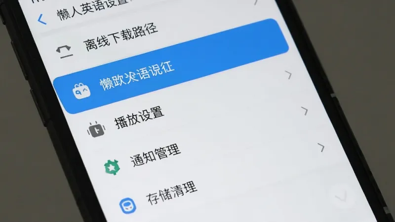懒人英语设置页面生图,手机屏幕显示设置菜单列表,包含离线下载路径、播放设置、通知管理、存储清理等选项,其中下载路径一栏高亮显示,界面为浅色主题,列表式布局,图标简洁,风格干净清爽,画质清晰