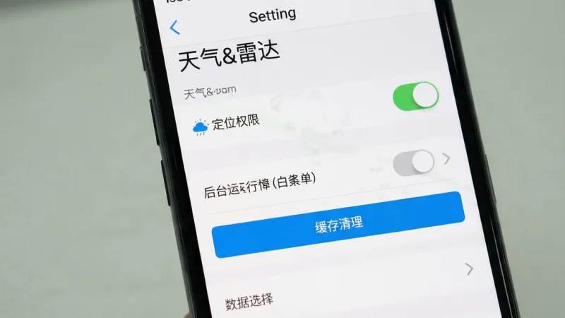 主体为手机屏幕展示天气&雷达应用设置页面,页面中包含定位权限开关、后台运行白名单、缓存清理按钮与数据源选择选项,屏幕上方有“天气&雷达”标题;布局为设置列表纵向排列,背景为浅色;排版清晰分组;风格为简洁工具类应用界面;细节包含开关按钮、箭头图标、灰色分隔线;画质高清,干净,无多余元素